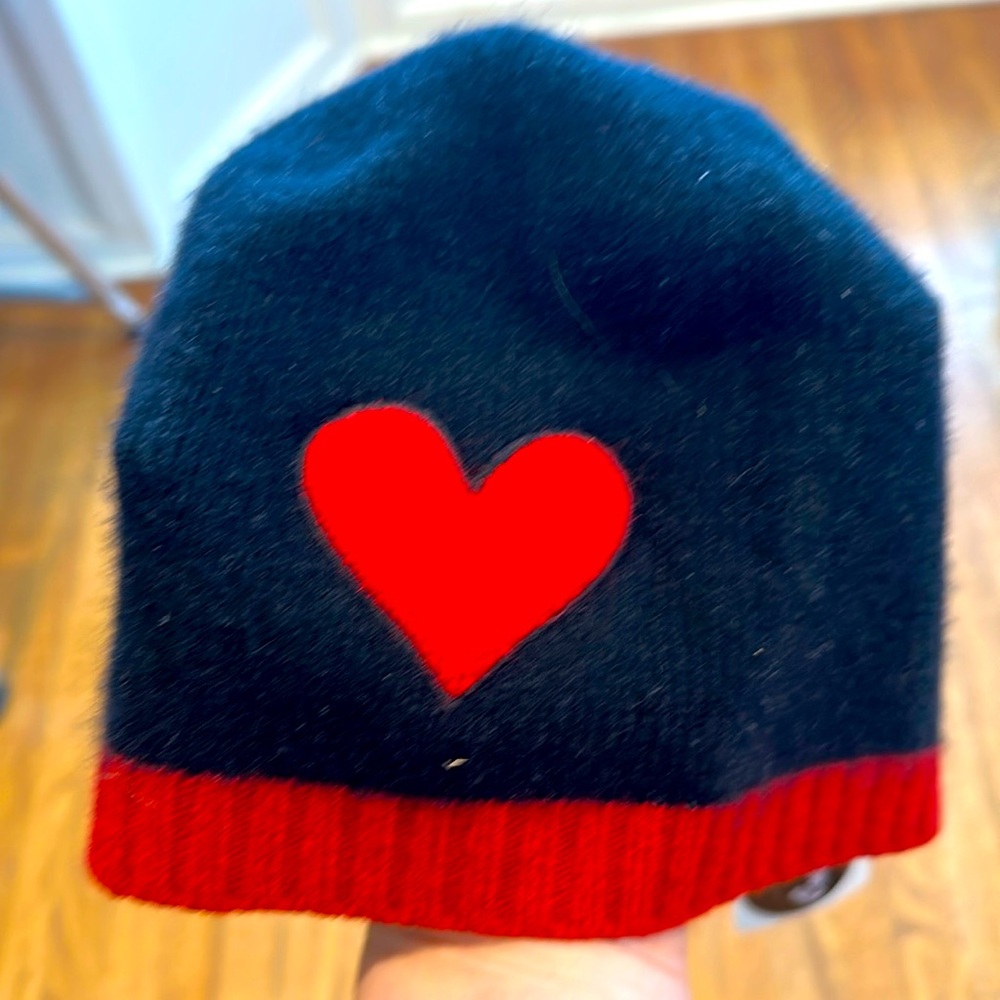 100% Cashmere women’s black hat with red trim and a red heart on it.